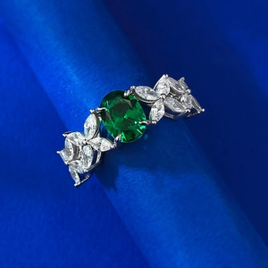 Detailed macro view of an oval emerald zircon ring with marquise-cut floral accents