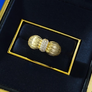 Vue macro d'une bague nœud dorée avec texture brossée et zircons dans un écrin à bijoux