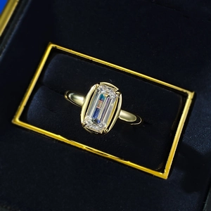 Macro shot of emerald cut diamond ring with gold band inside a luxury blue velvet box