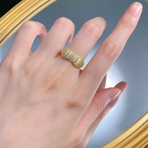 Détail d'une bague nœud dorée avec texture brossée et zircons pavés scintillants
