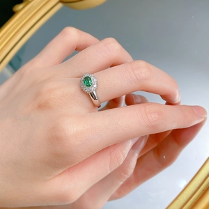 Close-up of S925 silver ring featuring an oval green emerald and a halo of diamonds