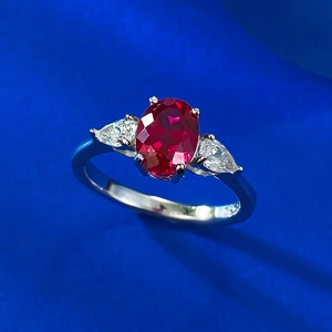 Macro view of oval red corundum ring with pear-shaped side stones in silver setting