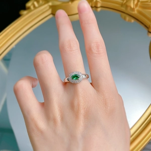 Macro detail of an oval green emerald-style ring with double halo pavé zircon stones