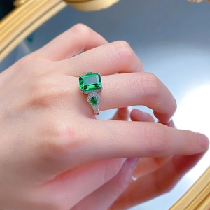 Détail d'une bague en argent S925 avec émeraude et pierres latérales sur miroir poli