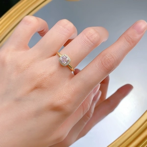 Détail d'une bague diamant rose carré sur une main avec reflets de miroir d'or
