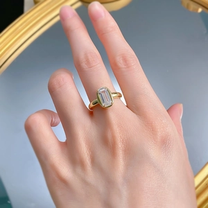 Detailed close-up of emerald-cut gemstone on a gold-plated sterling silver ring worn by a model
