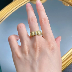 Gros plan d'une bague nœud dorée avec texture brossée et détails en zircon micro-sertis