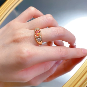 Close-up of sunset orange oval-cut gem ring in rose gold setting on finger with reflection