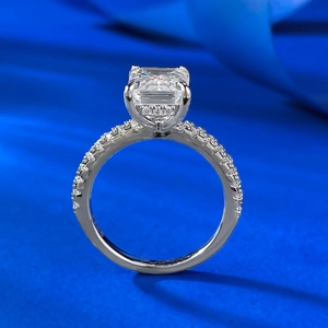 Macro view of emerald cut diamond ring with pave shank on dark blue satin fabric