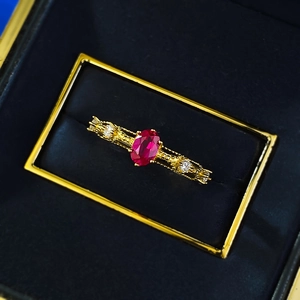 Macro shot of oval pigeon blood red ruby ring with gold bark texture in a blue velvet box