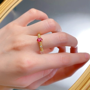 Detailed view of an oval pigeon blood red stone ring with gold band and floral engraving