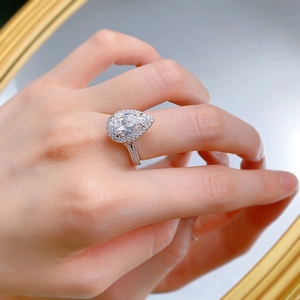 Close-up of S925 silver pear-cut halo engagement ring on finger with shining diamonds
