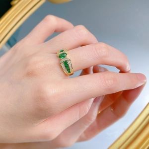 Close-up of gold-plated S925 silver ring featuring emerald stones and micro-pave diamonds