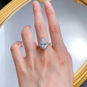 Macro detail of a 925 silver pear-cut drop ring with halo diamond accents on hand