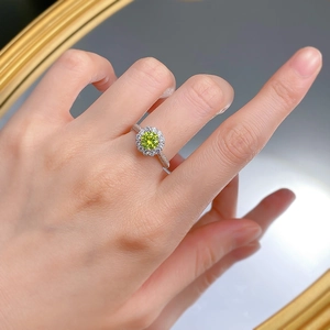 Gros plan d'une bague halo vert pomme avec de petits diamants sur un anneau argenté