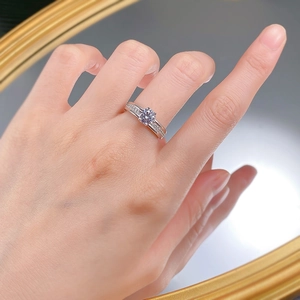 Close-up of 6mm round cut cubic zirconia ring with side accent stones on a model's finger
