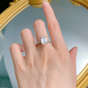 Detail of emerald cut rectangle zircon ring with pave diamond band on model finger