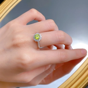Vue détaillée d'une bague halo vert pomme avec pierre ronde sur la main d'un mannequin