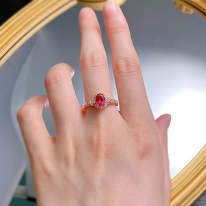 Close-up of S925 silver ring with oval ruby and rose gold band on a hand