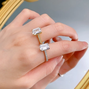 Close-up of gold and silver rectangular cut rings featuring pave-set bands on a hand