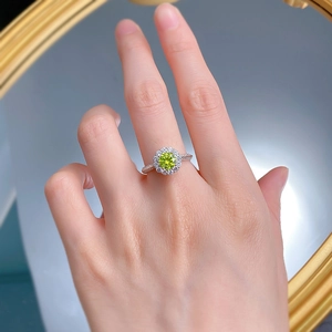 Détail de la bague diamant vert pomme avec halo tournesol portée à la main