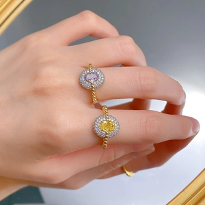 Close-up of luxury gold beaded rings featuring oval yellow and purple gemstones with halos