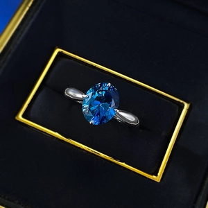 Macro shot of oval royal blue stone ring with 4-prong silver setting in a black velvet box