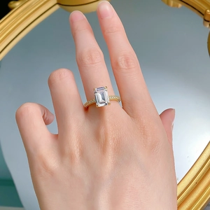 Detail of emerald cut gemstone ring on finger with elegant mirror background