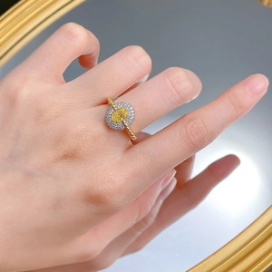 Detailed shot of halo ring with yellow gemstone and golden beaded band on finger