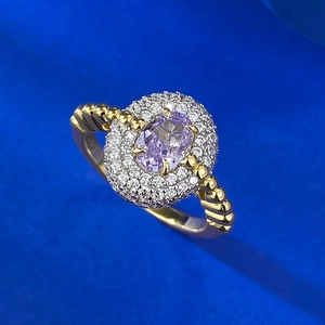 Macro detail of oval purple gemstone ring with diamond halo and gold rope twist band