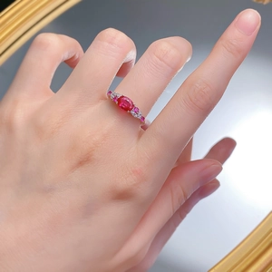 Close-up of S925 silver ring with oval ruby and sparkling zircon accents on finger