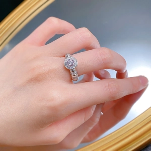 Macro shot of 925 silver ring with halo-set pink round gemstone on a mirrored surface