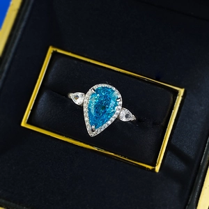 Macro view of pear cut blue gemstone ring set in a premium velvet display box