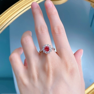 Détail d'une bague en argent 925 avec une pierre rouge ronde entourée d'un halo brillant
