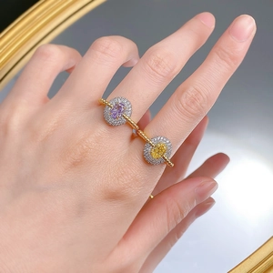 Close-up of double-finger gold ring with purple and yellow oval gemstones on hand
