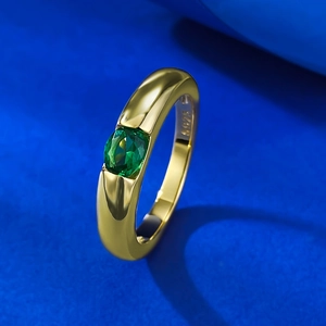 S925 gold plated silver ring with oval green gemstone on a bright blue background
