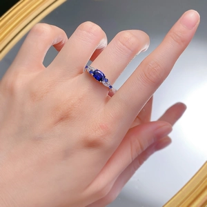 Close-up of an oval blue gemstone ring with micro-pave accents on silver band