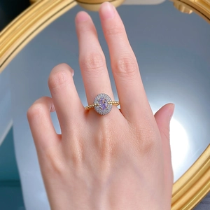 Elegant gold-plated ring featuring an oval purple gemstone with a double halo on finger