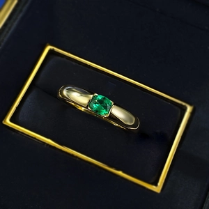 Close-up of gold-plated silver ring with square green gemstone in a blue jewelry box
