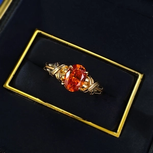 S925 silver ring with oval orange gemstone and intricate gold wire wrap in a jewelry box