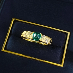 Macro detail of S925 gilded ring with sugarloaf emerald zircon and brushed metal texture
