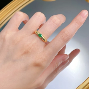 Close-up of gold-plated silver ring with an oval green gemstone on a mirror