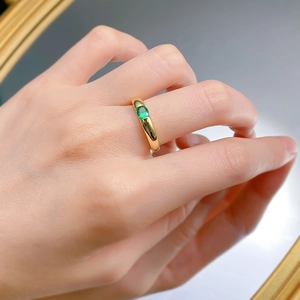 Detail view of a 925 silver gold-plated ring with a green oval gemstone on a model hand