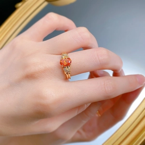 Macro shot of an oval orange gemstone ring with a unique twisted gold-plated band