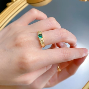 Detailed macro view of gold brushed ring with green sugarloaf gemstone and small diamonds