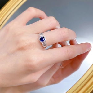 Detail eines quadratischen königsblauen Saphirrings an einer Hand mit Diamanten