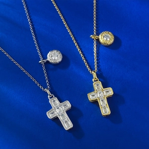 Macro detail of gold and silver cross pendants with zircon stones on a blue background