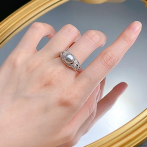 Macro detail of luxury ring featuring 8mm grey pearl and silver diamond-set carving