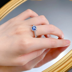 Détail d'une bague en argent S925 avec une pierre bleue taille coussin et halo serti