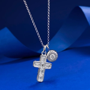Macro shot of S925 silver cross and round zircon pendant on blue silk background